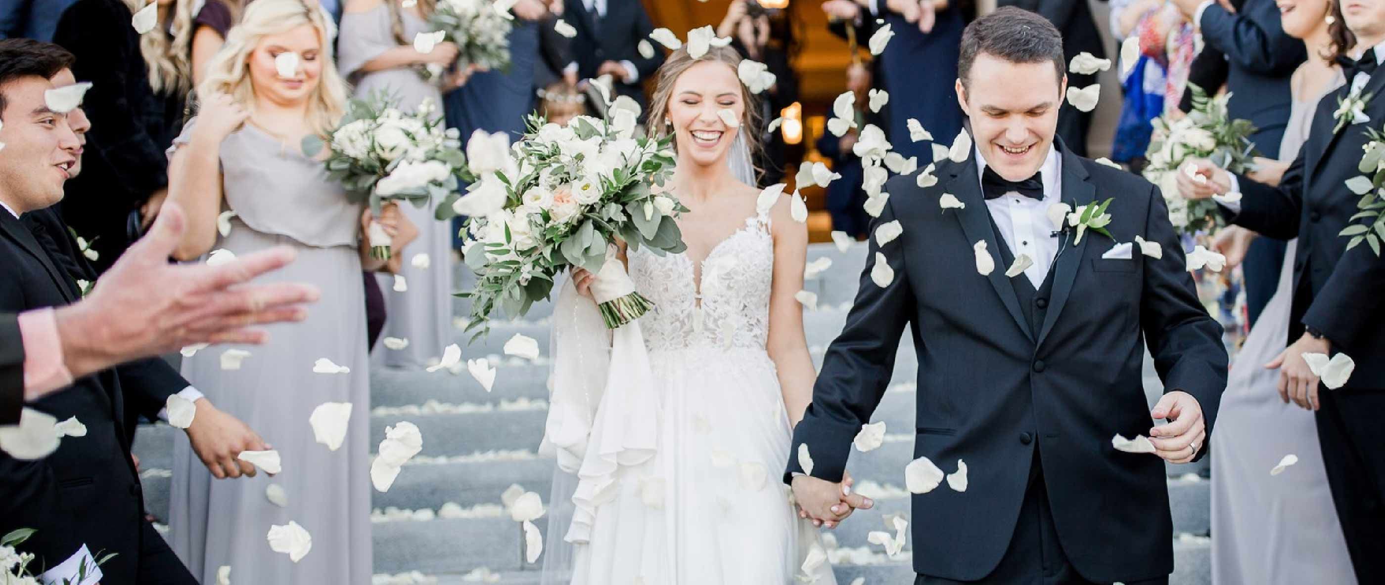 Сouple wearing a white gown and a black suit. Mobile image